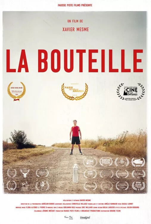 Αφίσα ταινίας "La Bouteille". Ένας μοναχικός άνδρας δρομέας με κόκκινο αμάνικο μπλουζάκι στέκεται σε χωματόδρομο, κοιτάζοντας ένα διαφανές πλαστικό μπουκάλι στο έδαφος μπροστά του. Ξηρά χωράφια πλαισιώνουν το μονοπάτι κάτω από έναν φωτεινό ουρανό.